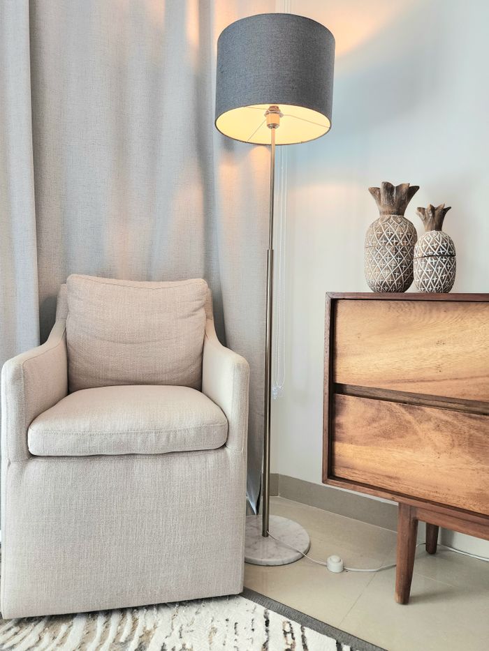 about-02 Elegant modern living room with armchair, lamp, and wooden dresser. Warm and inviting atmosphere.