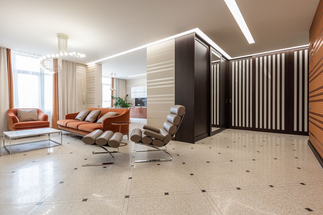 services-01 Interior of modern flat with spacious corridor and comfortable seats in living room with kitchen counter in distance at home